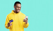 © Prostock-studio - Mobile Shopping. Happy African American Man Using Credit Card And Cellphone Purchasing Something In Online Shop Application Standing Over Blue Studio Background. E-Commerce Concept