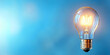© Crealif76 - Illuminated Light Bulb Against a Blue Background.