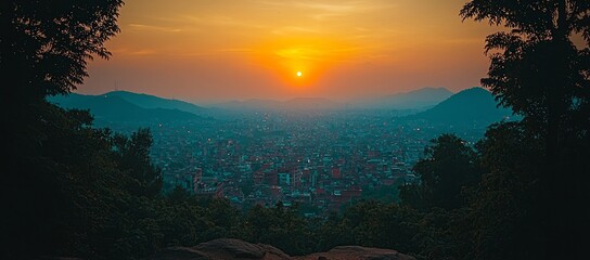 Wall Mural - Panoramic sunset view over a sprawling city nestled in a valley, framed by lush green hills.