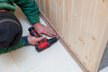 Wall Mural - A man is using a power drill to make a hole in a wooden board