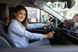 © Graphicroyalty - Happy woman in new car. Beautiful girl looking through the car window. Business woman choosing new car in car dealership