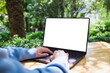 © Farknot Architect - Mockup image of a woman using and typing on laptop computer touchpad with blank white desktop screen in the outdoors