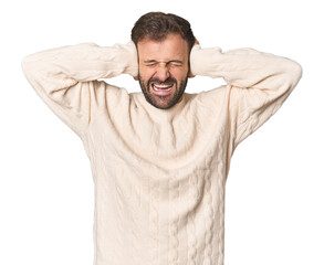 Wall Mural - Studio portrait of young Hispanic male covering ears with hands trying not to hear too loud sound.