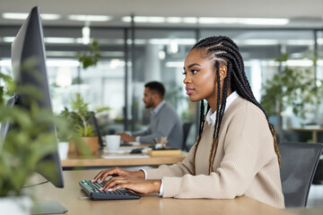 Poster - Woman typing on a keyboard in a modern office environment.
