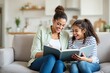 © Pixels Hunter - Mother and daughter enjoying a book together on a cozy couch in a well-lit modern home background.