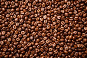 Close-up of roasted coffee beans background with warm lighting creating a rich texture and shiny highlights.