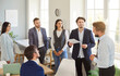 © Studio Romantic - A group of six professionals engaged in a discussion during a meeting in a contemporary office. Two men present information while colleagues listen attentively and take notes.