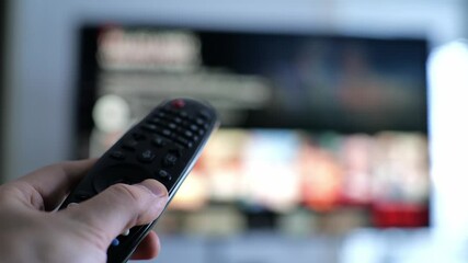 close up of hand using tv remote control to browse streaming application on smart tv