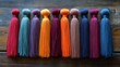 © ArtCookStudio - Colorful tassels arranged in a row on a wooden surface for craft and design projects