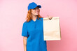© luismolinero - Young caucasian woman taking a bag of takeaway food isolated on pink background looking to the side and smiling