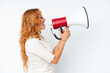 © luismolinero - Young caucasian woman isolated on white background shouting through a megaphone to announce something in lateral position