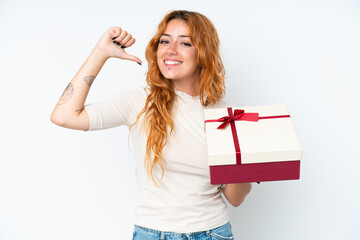 Wall Mural - Young caucasian woman holding a gift iso0lated on white background proud and self-satisfied