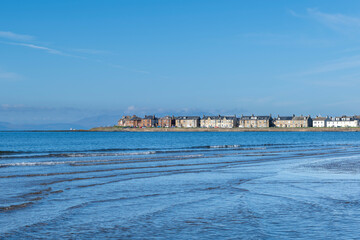 Looking over the waters of Troon Bay Bay in Scotland with blue Skys and gentle waters lapping the beach.