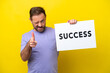 © luismolinero - Middle age caucasian man isolated on yellow background holding a placard with text SUCCESS and pointing to the front