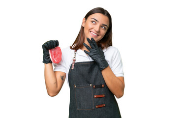 Wall Mural - Butcher woman wearing an apron and serving fresh cut meat isolated on green chroma background looking up while smiling