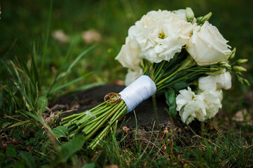 Wall Mural - Elegant Wedding Bouquet with Roses and Wedding Rings on Green Grass