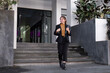 © wichayada - Confident Businesswoman Walking and Talking on Phone in Urban Cityscape