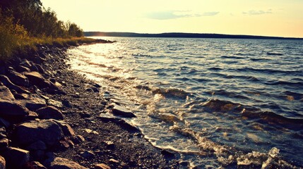 Poster - A serene lakeside scene with gentle waves and a rocky shore under a warm sunset glow.
