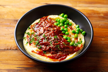 Wall Mural - Mashed potatoes with beef meat and green peas in bowl. Wooden background. Close up.