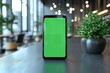 © neiros - A green screen smartphone rests on an uncluttered white desk in a modern office, shot with a shallow depth of field