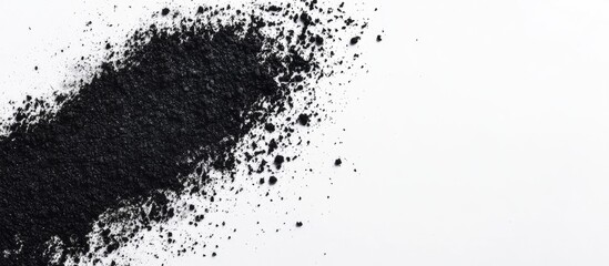 Poster - Black charcoal powder scattered on a white background with ample empty space for text or branding in a clean, minimalistic design.