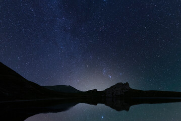 Wall Mural - Beautiful night landscape, Bright Milky Way galaxy over the small  lake and mountains.