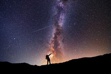 Wall Mural - Silhouette of a  hiker standing on the hill,  under milky way galaxy sky. Beautiful night landscape.