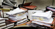 © Lane Erickson - Messy Desk with Books Binders Files and Papers Stacked up High in a Disorganized Office Space