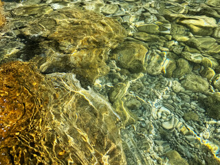 Wall Mural - Stones and pebbles in sea crystal clear water.