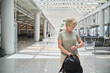 © Rowena Naylor/Stocksy - Traveler checking the time in a modern airport terminal during the day