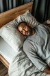 © Andrii Zastrozhnov - A man is sleeping on a bed with a white pillow. The man is wearing a gray shirt and has a beard