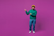 © ViDi Studio - Full body young happy smiling Indian man he wear green hoody yellow hat casual clothes point index finger aside on area mock up isolated on plain purple background studio portrait. Lifestyle concept.