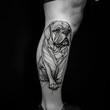 © Anastasiia - Detailed black and gray tattoo of a seated dog on a person's leg in a dimly lit space