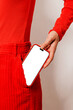 © BONNINSTUDIO/Stocksy - Woman pulling smartphone with blank screen from red pocket