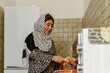 © Anna Fedorova/Stocksy - Smiling afghan woman peeling a carrot at the kitchen
