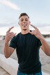 © Ezequiel Giménez/Stocksy - Young man showing tongue and rock and roll hand gesture outdoors