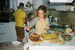 © Duet Postscriptum/Stocksy - A young housewife piles food on a plate before a family dinner party