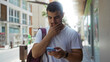 © Krakenimages.com - Young hispanic man checking his phone while standing on an urban street in the city during daytime