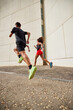 © Javier Díez/Stocksy - A pair of runners sprinting together in the street