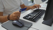 © Krakenimages.com - Man holding credit card and typing on keyboard in modern office setting