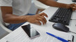 © Krakenimages.com - Young man working at a desk in an office using a computer keyboard with documents and a smartphone nearby