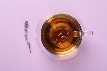 Wall Mural - Aromatic lavender tea in glass cup and dry flower on pink background, top view