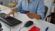 © Krakenimages.com - Woman holding credit card while working on computer in office setting, depicting a professional environment with a focus on online transactions and digital payments.
