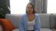 © Krakenimages.com - Young hispanic woman sitting in a modern living room with orange cushions and plants