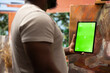 © DC Studio - Young artist looking at isolated chroma key display in his painting atelier, using device next to canvas with a colorful masterpiece. Painter creating a rustic artwork for the gallery exhibition.