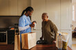 © BONNINSTUDIO/Stocksy - Caregiver bringing groceries and milk bottle to elderly woman