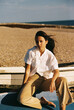 © Polina Kovalova/Stocksy - A stylish girl sitting on top of an old boat on the beach