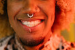 © VICTOR TORRES/Stocksy - Close-up of smiling lips with facial piercings in warm lighting