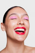 © Ángela Rober/Stocksy - Laughing Woman with Bold Red Lips and Vibrant Pink Eye Makeup