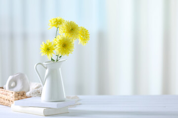 Wall Mural - Beautiful yellow flowers in vase and books on white wooden table at home. Space for text